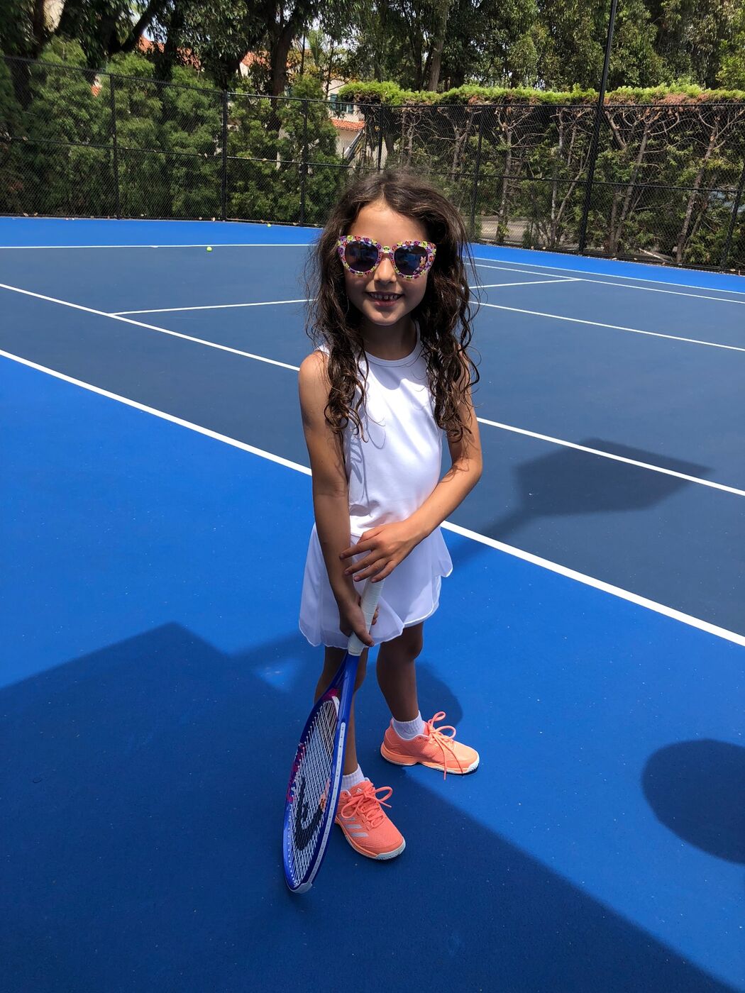Gabi in ready position holding racket low on a blue court