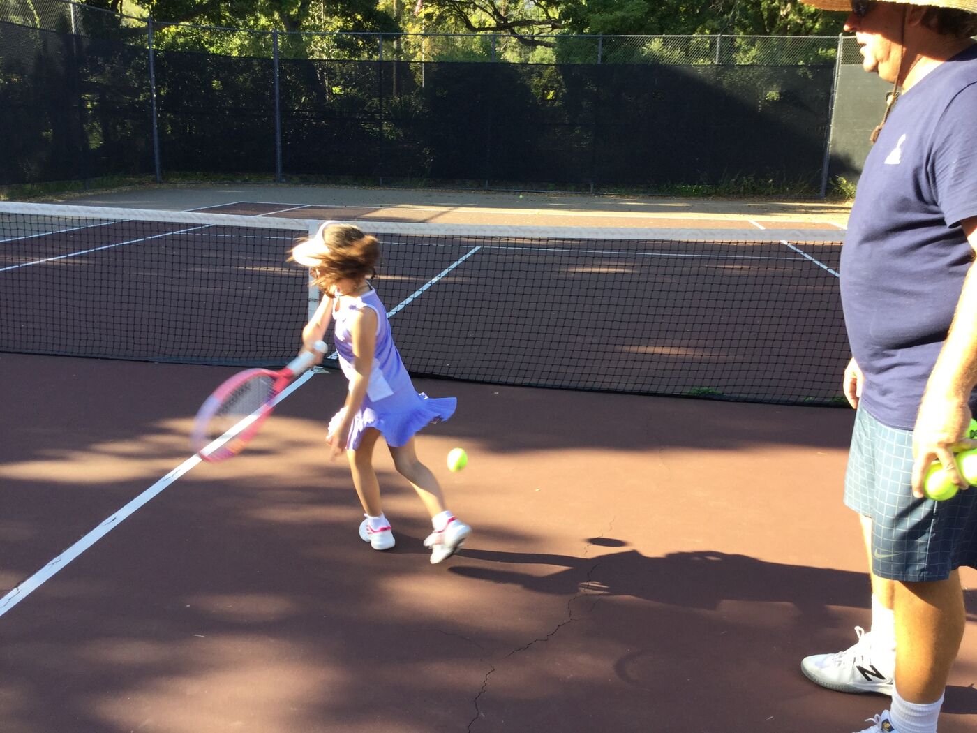 Young Gabi running down a forehand with Coach Jay watching
